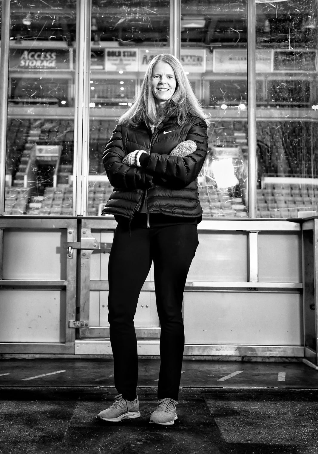 A black and white image of a woman standing near a hockey rink
