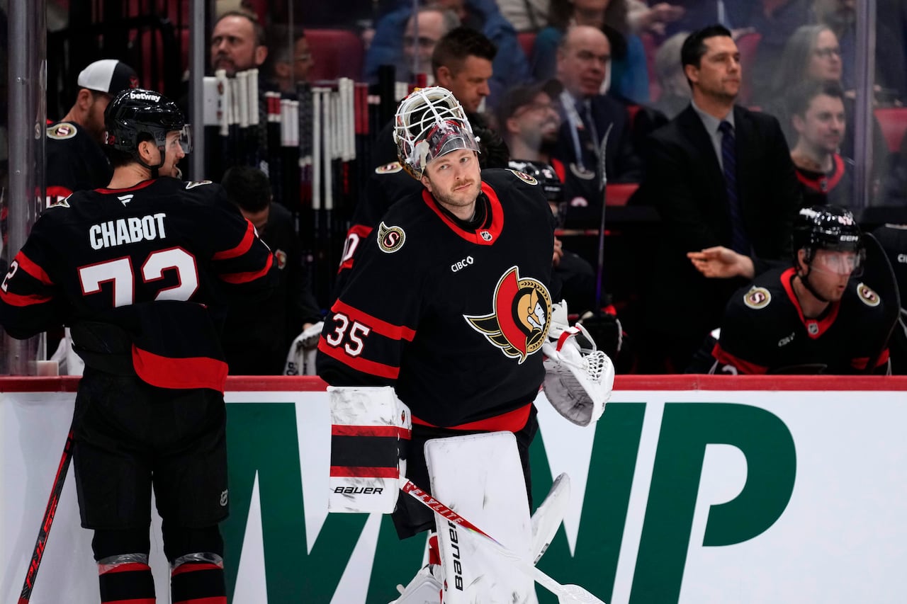 A professional hockey goalie with his mask above his head skates past his team's bench.