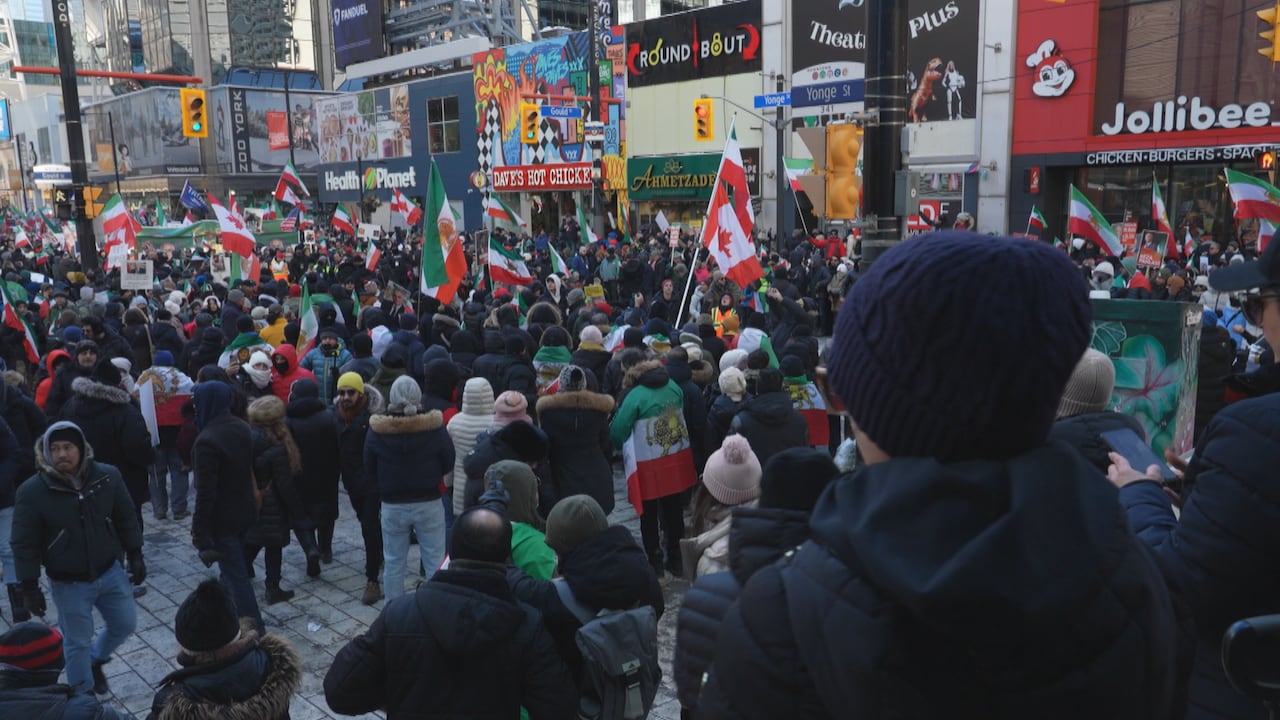 Large group of protesters standing by TMU's campus holding flags and posters