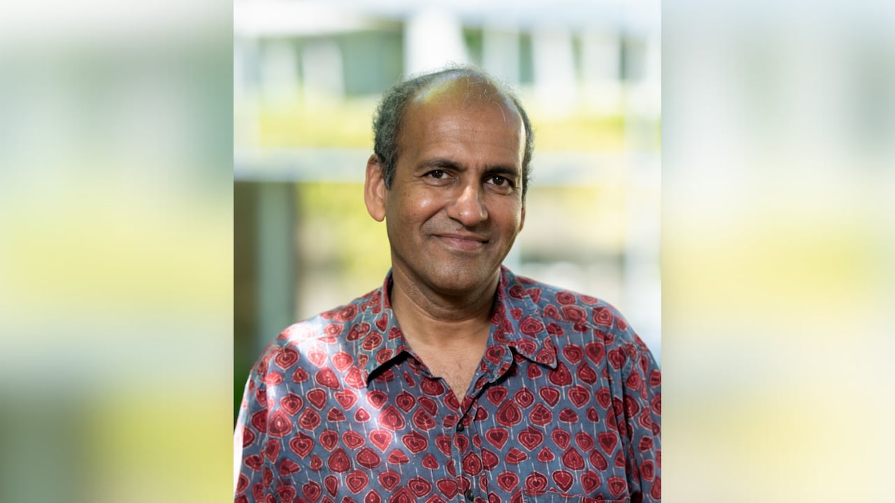 A person wearing a red and blue patterned dress shirt is seen standing outside.