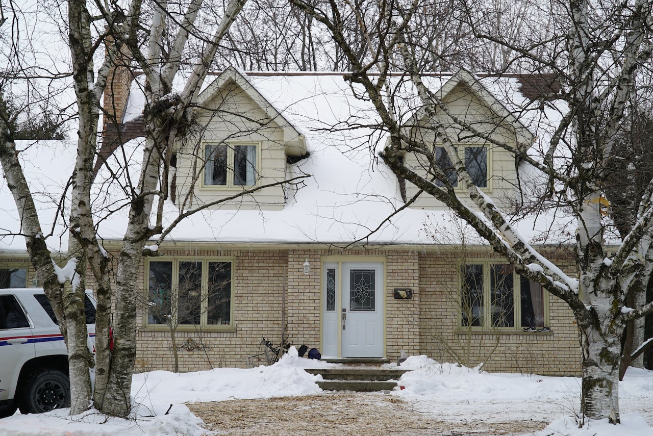 A beige house covered with snow on the ground 