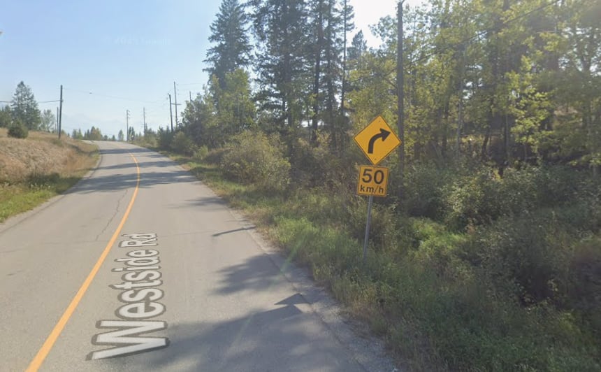 A curve in the road with a yellow sign indicating a 50 km/h speed limit