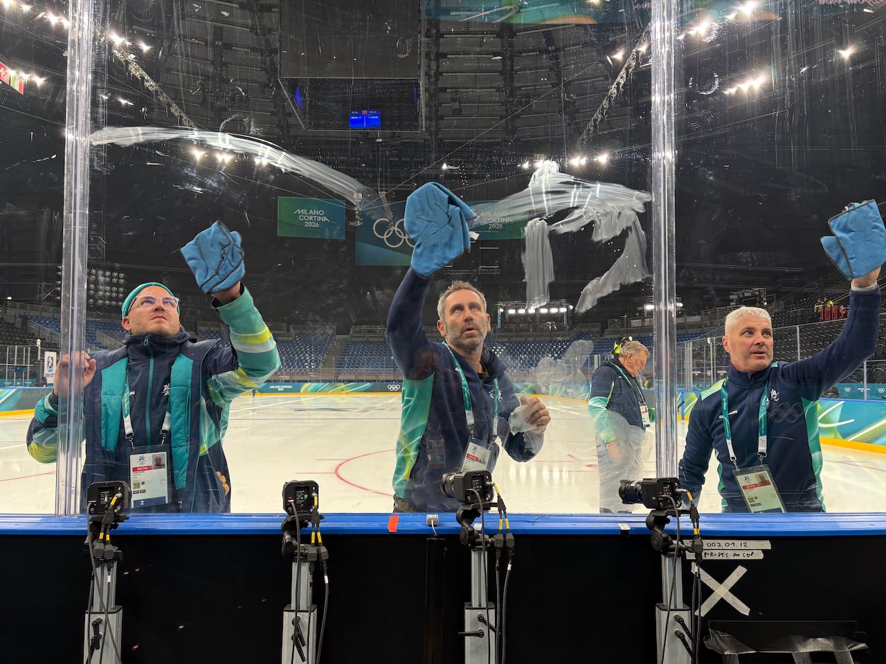Workers clean rinkboard glass.
