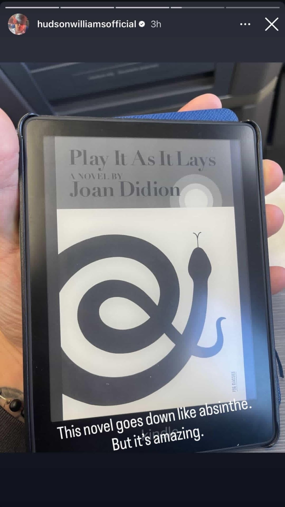 an Instagram story of a hand holding an e-reader with a black and white cover of Play It As It Lays by Joan Didion.