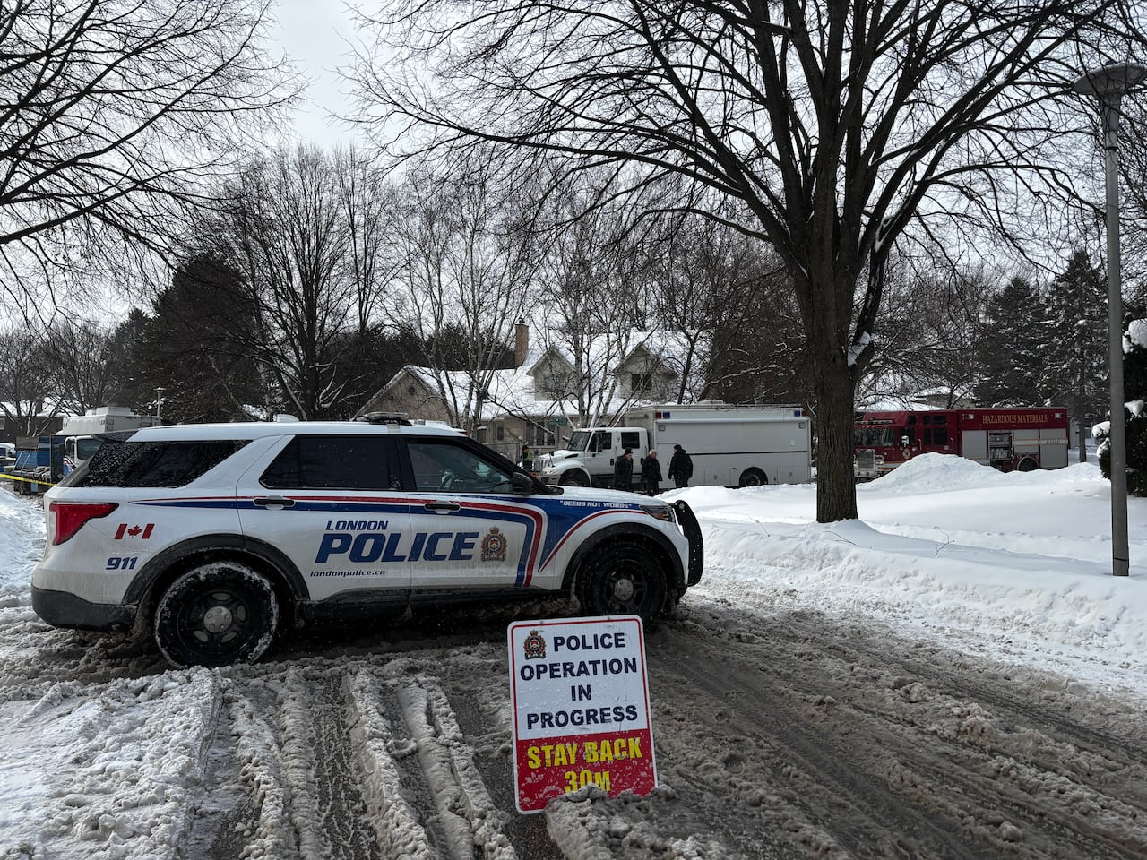 Police car parked with a sign telling people to stay back on a winter street.
