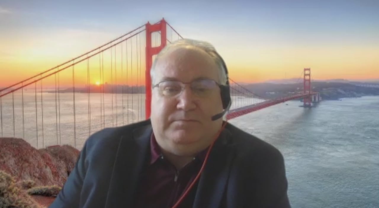 A man on a video call, wearing a headset, with a stock photo background image.
