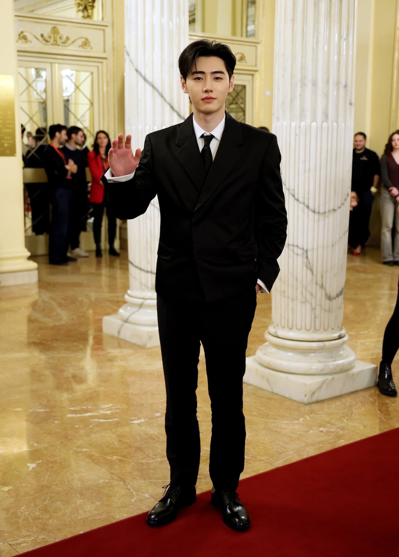 A man poses for a photo in a black suit. 