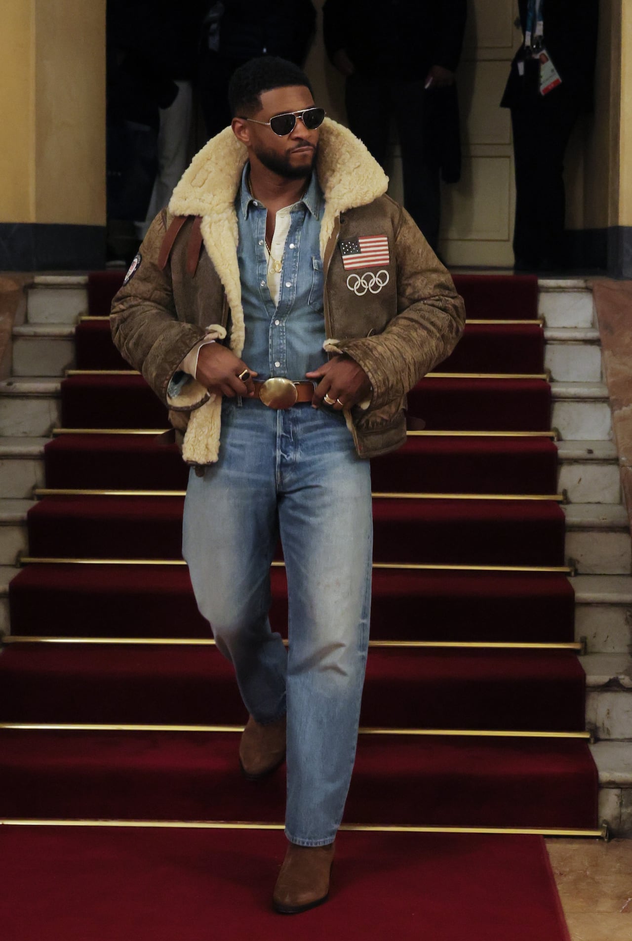 A man poses for a photo in denim top and jeans with western boots and a distressed leather jacket lined with shearling