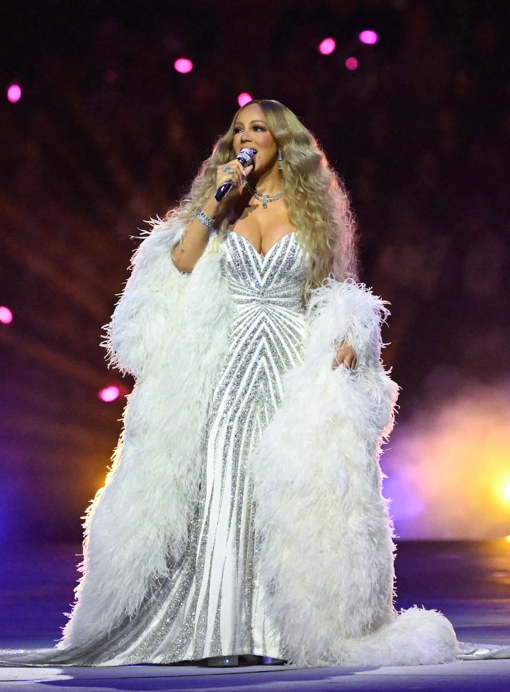 A woman singing on stage wearing a sequinned gown. 