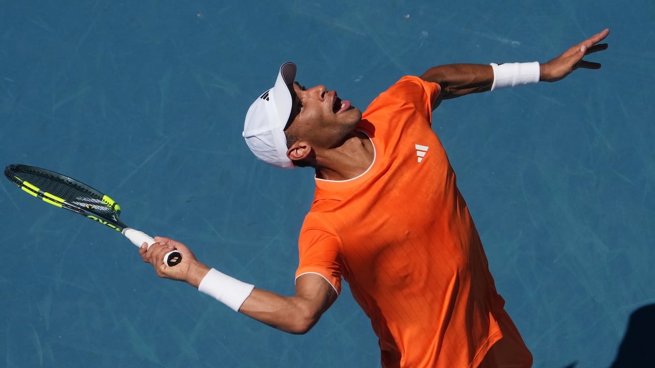 A male tennis player serves during a game.