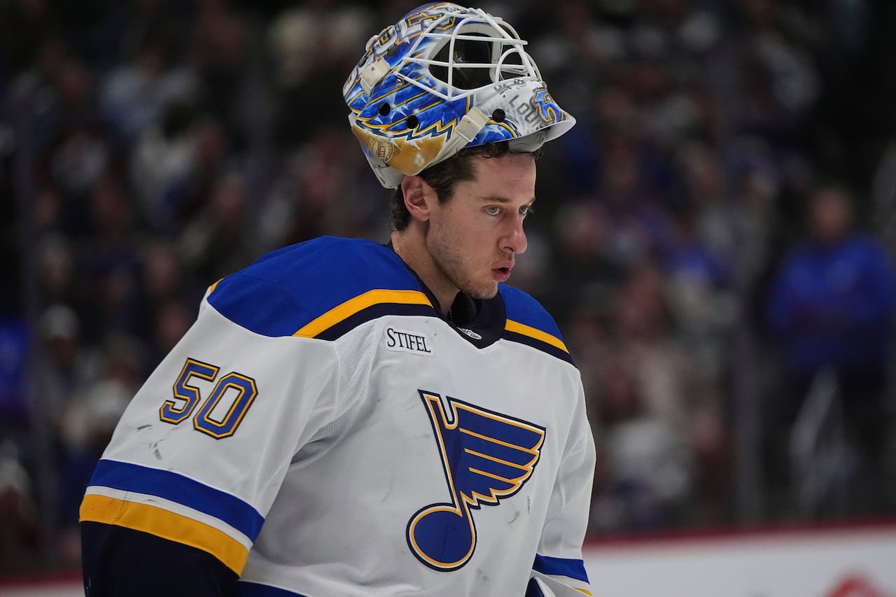 A goaltender with his mask up looks on.