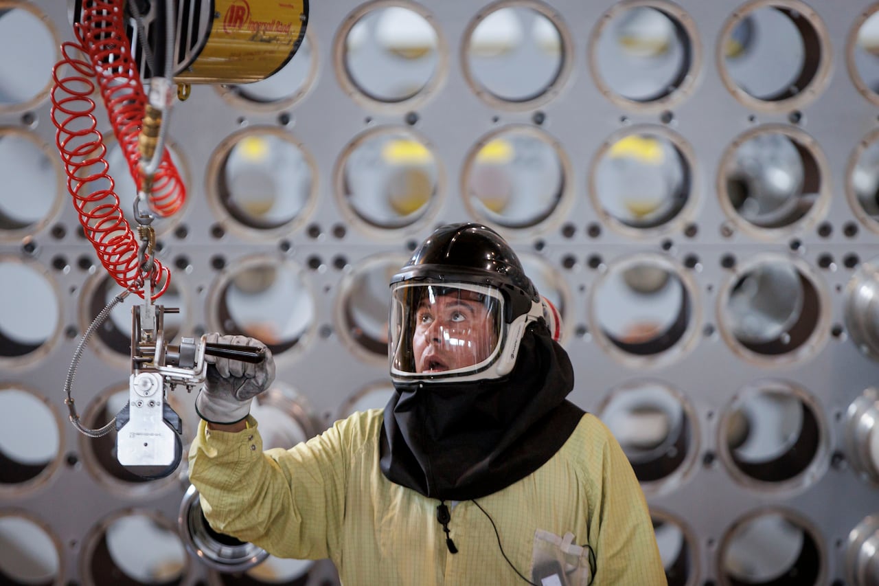 A person in a hazmat suit operates machinery
