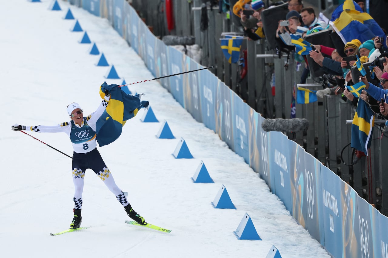A woman skier waves a flag.