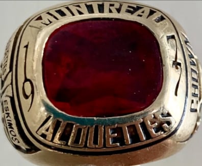 A red gemstone encrusted into a gold ring that says Montreal Alouettes.