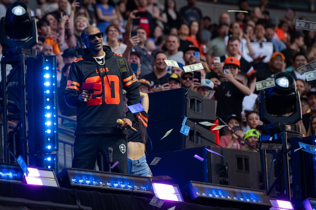 Snoop Dogg shoots fake money as he performs.