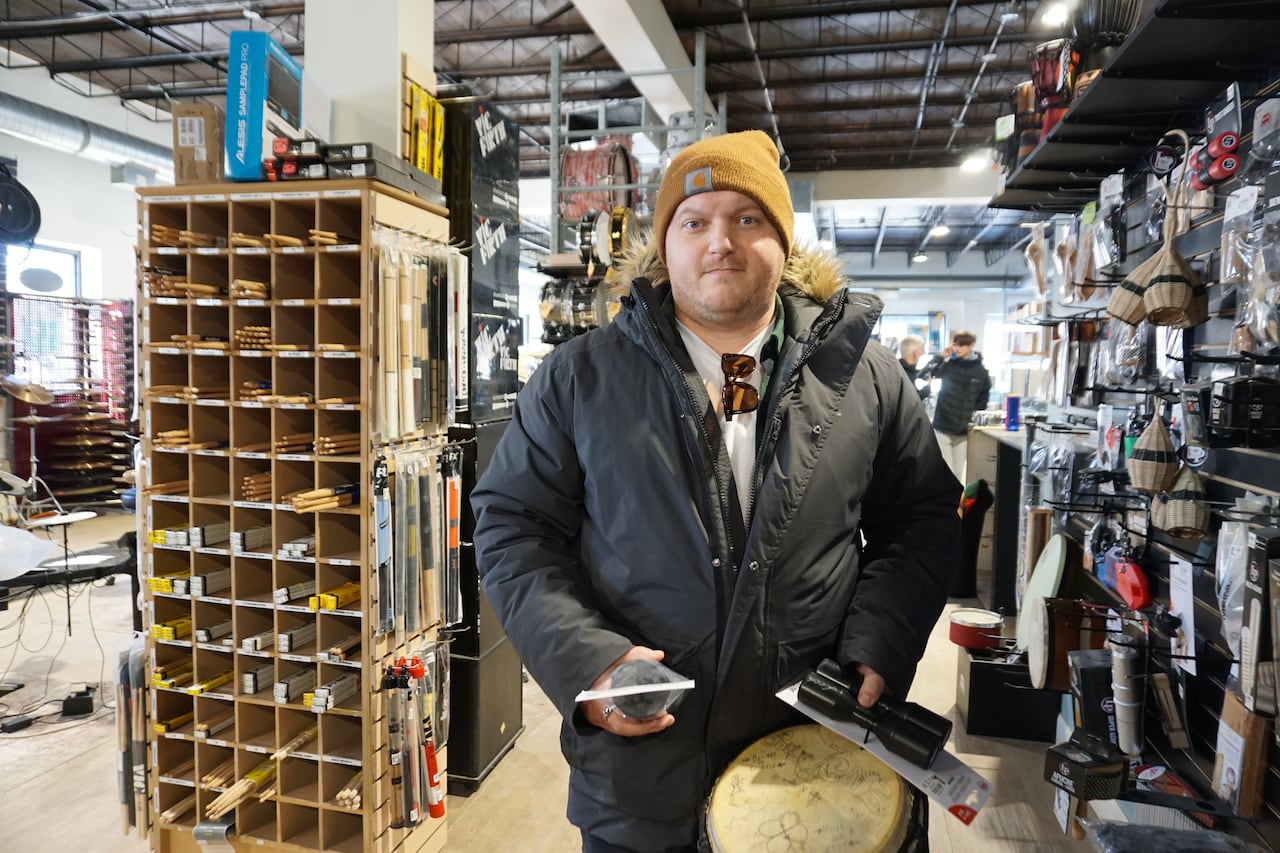 a man holding a few shakers and a bongo.