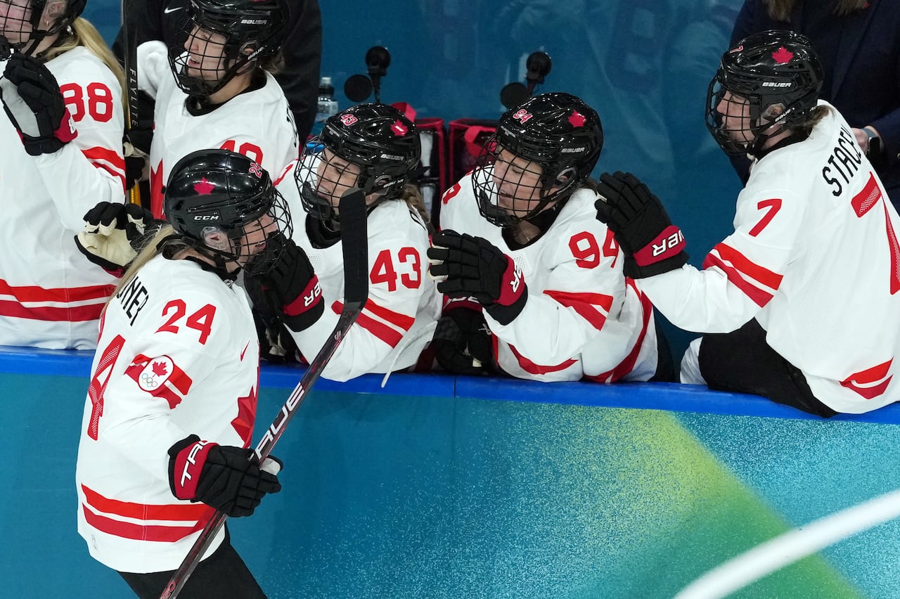 A Canadian hockey player celebrates with teammates on the bench.