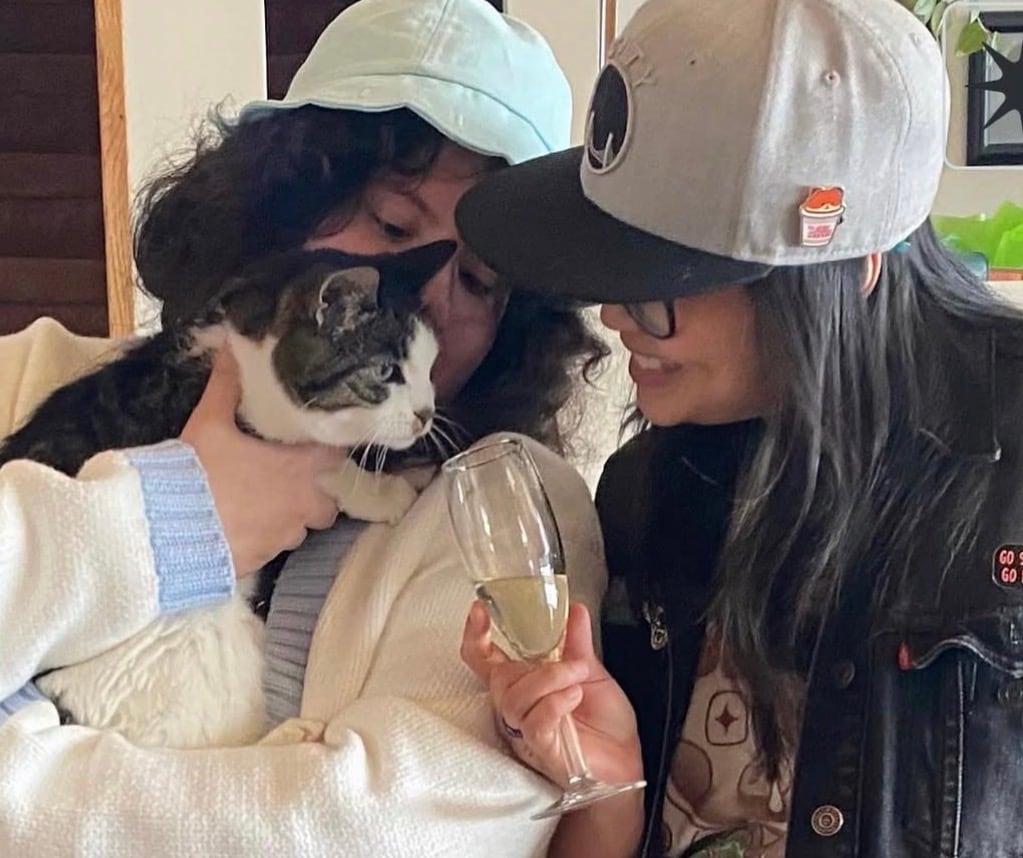 A couple cuddles with a cat.