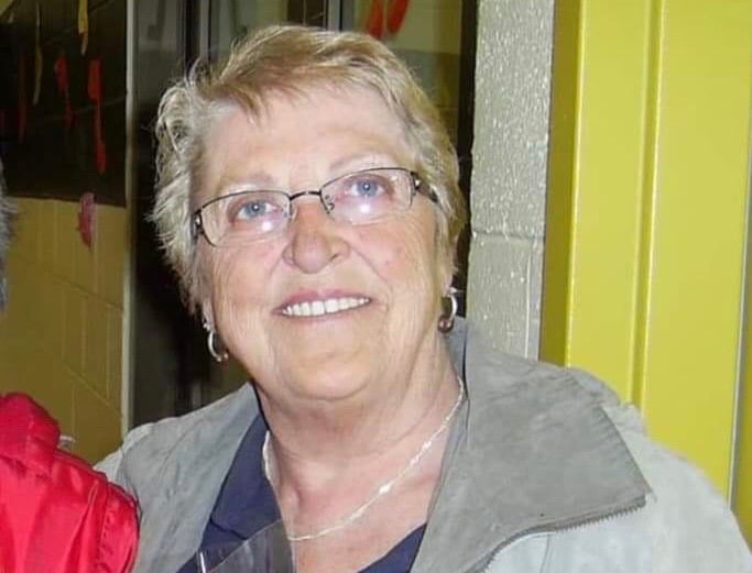 an older woman wearing glasses smiles for the camera