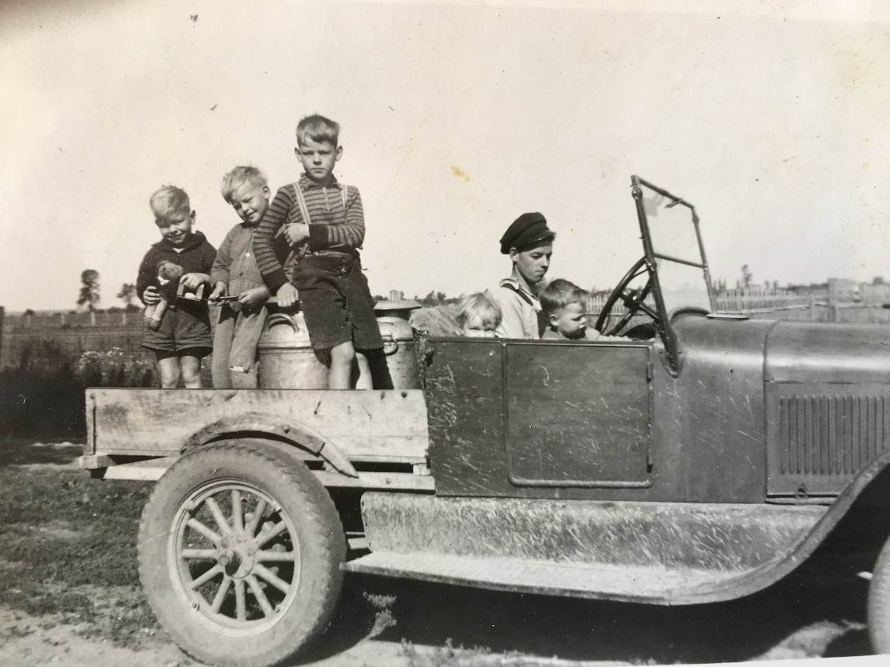 A black and white photo shows a family in a truck delivering milk in the 1940s. 