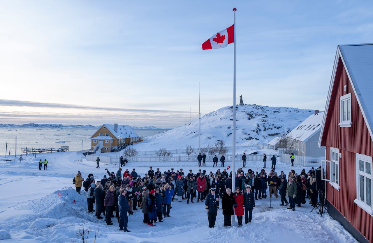 A crowd of people observe a flag raising.
