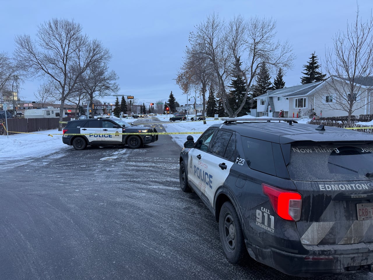 Police vehicles and police tape are seen on a street.