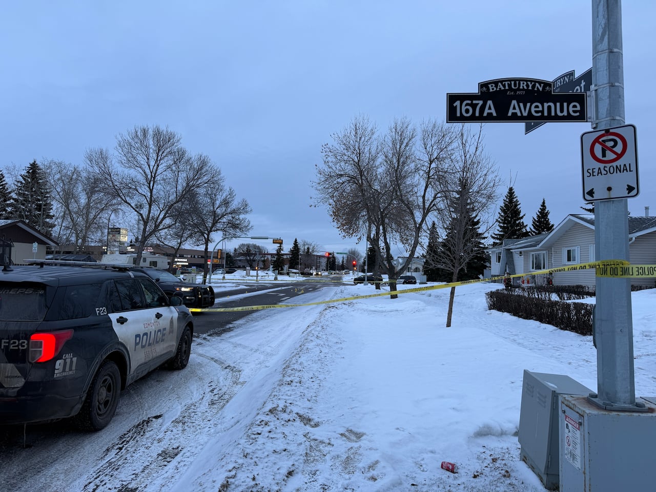 Police vehicles and police tape are seen on a street.