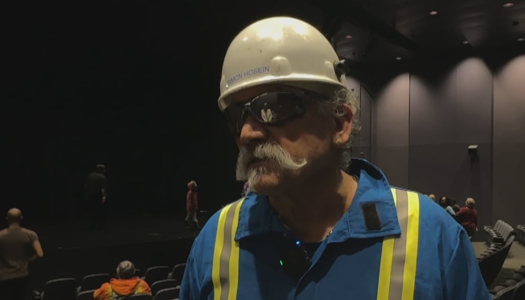 A man standing wearing the oil and gas uniform, with his safety helmet and glasses on. 
