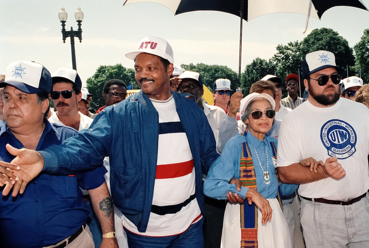 Four people are shown walking outside with arms linked.
