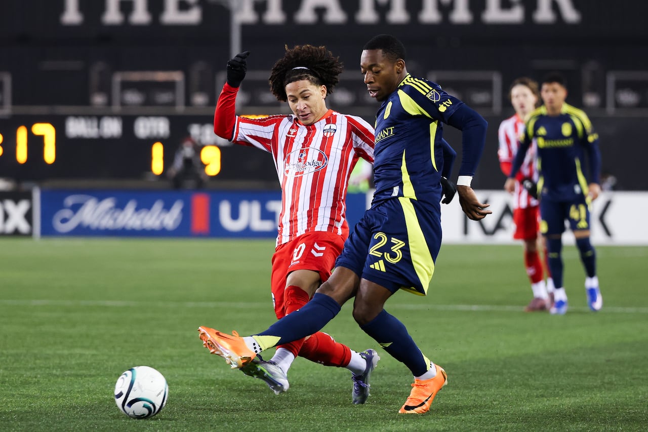 Two soccer players jostle for a ball.