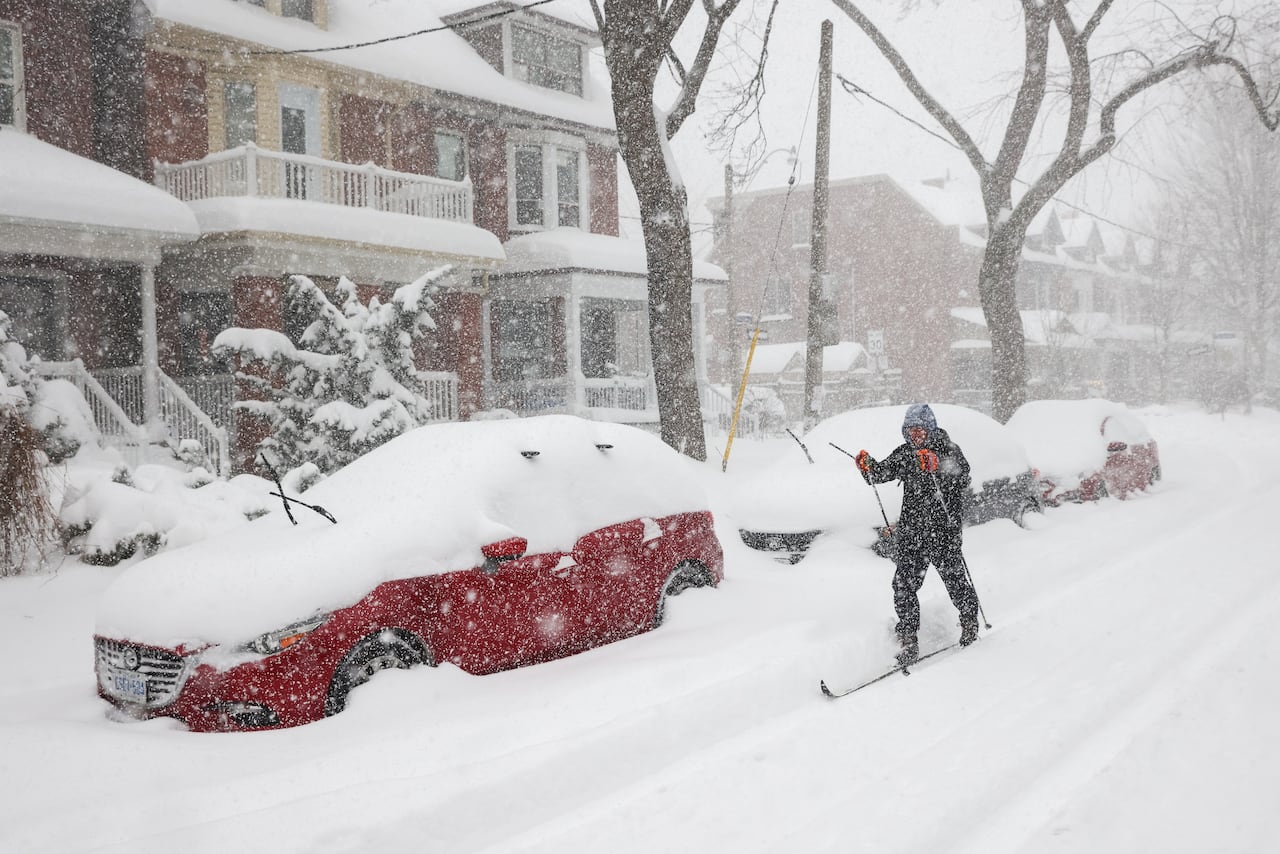 A person using cross-country skis on a snow-covered city street in Toronto