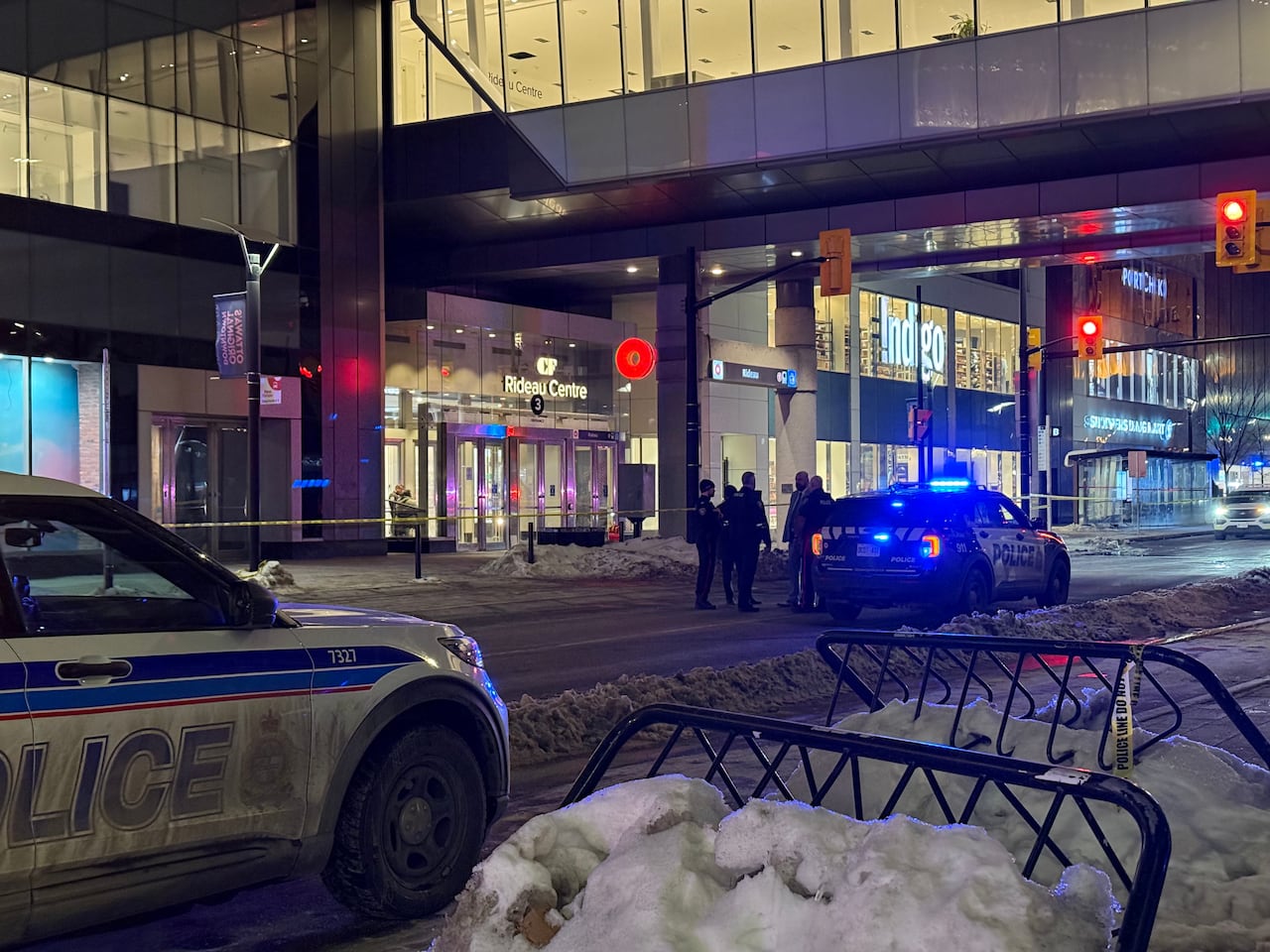Police standing in the middle of the street outside a mall.