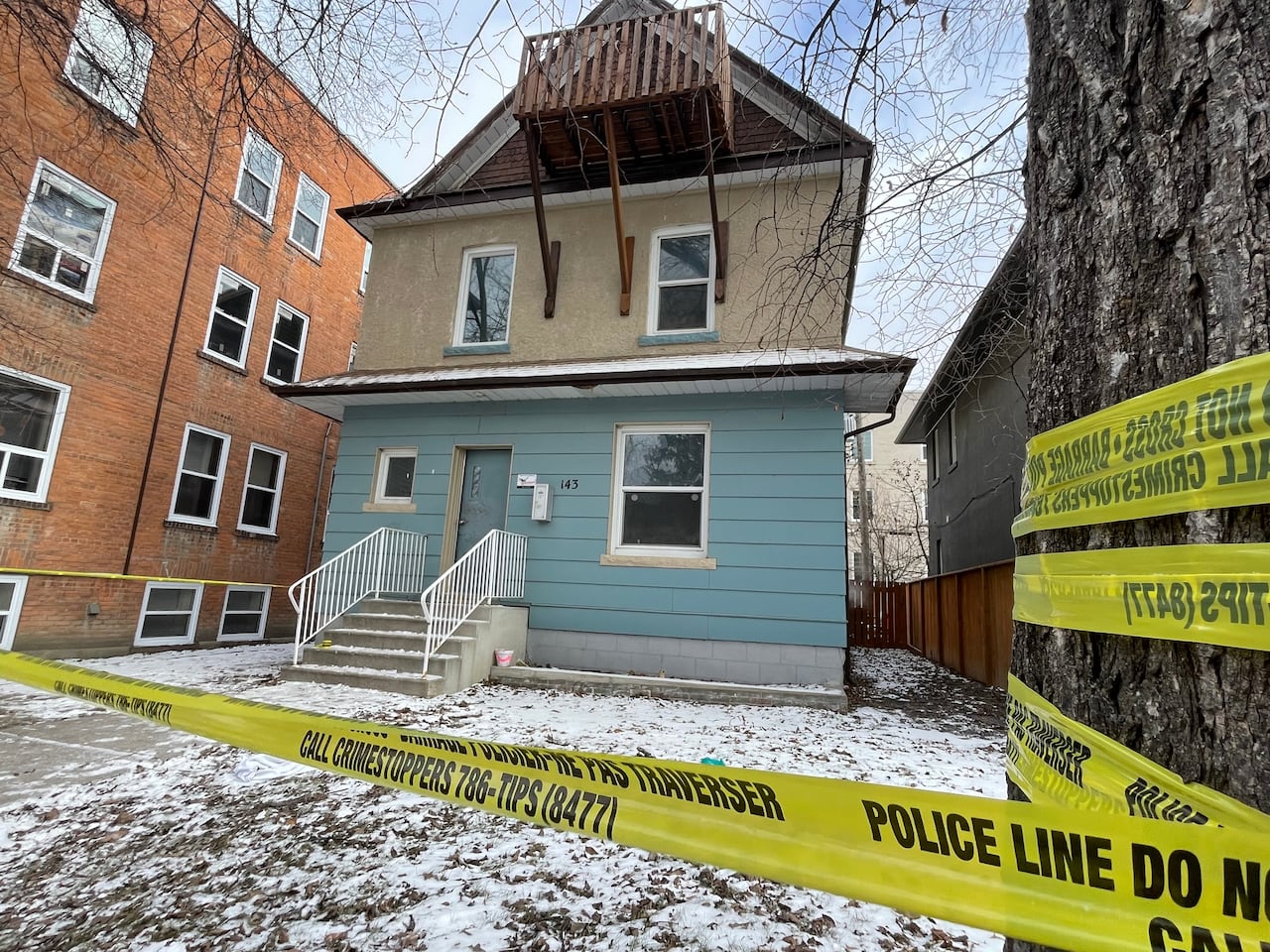 A home with blue and tan paneling is surrounded by police tape. 