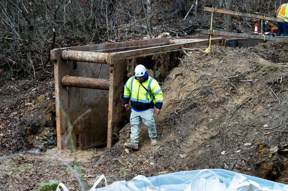 A worker wearing boots and a hard hat walks past part of a cofferdam being built to stop the flow of raw sewage into the Potomac River after a massive sewage pipe rupture in Maryland in January.