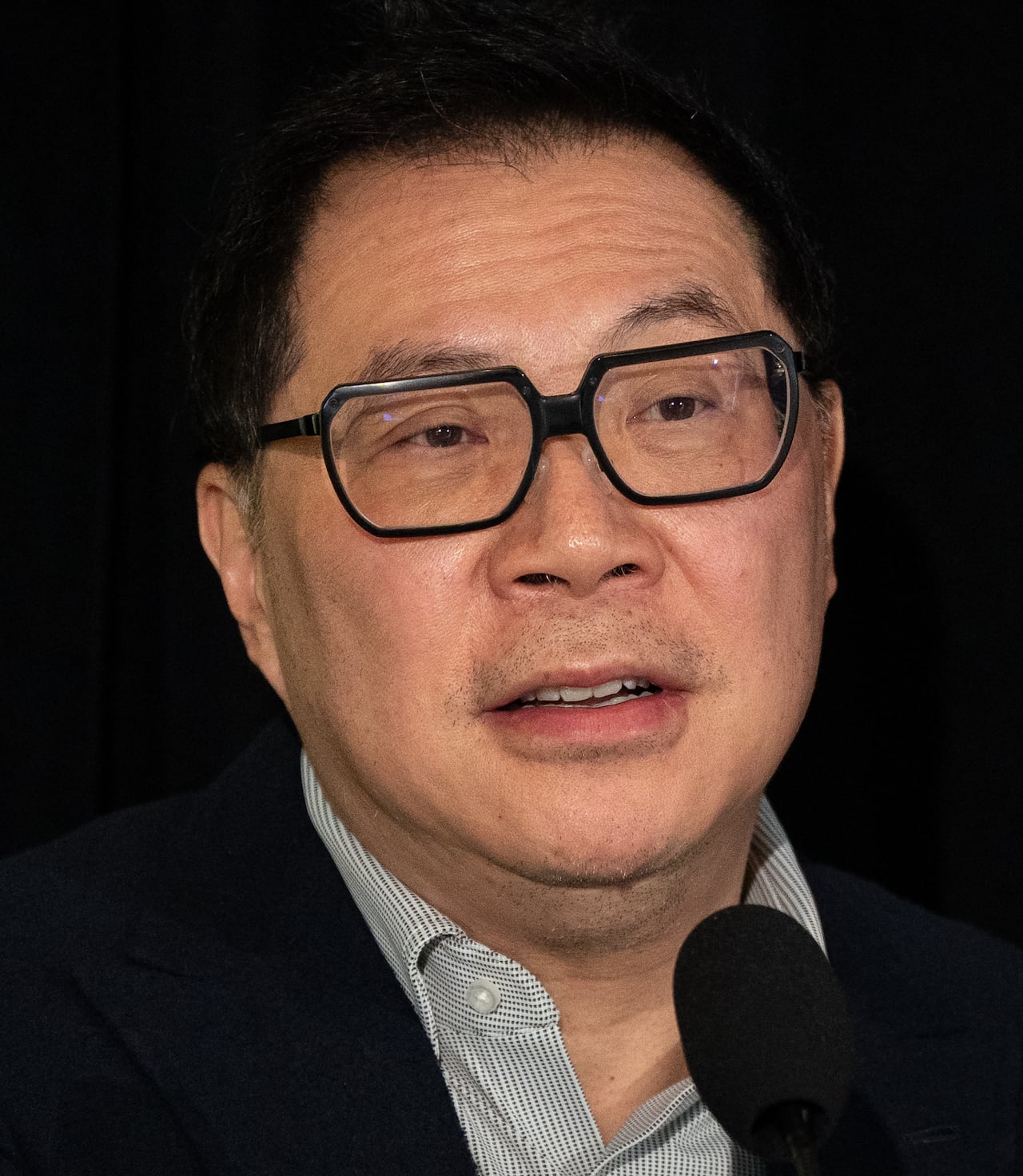 An East Asian man speaks into a mic.