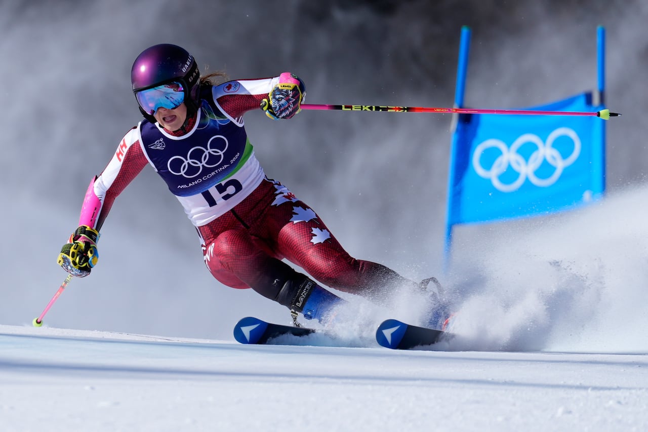 A woman wearing red and white suit emblazoned with maple leaves flies along a ski course.