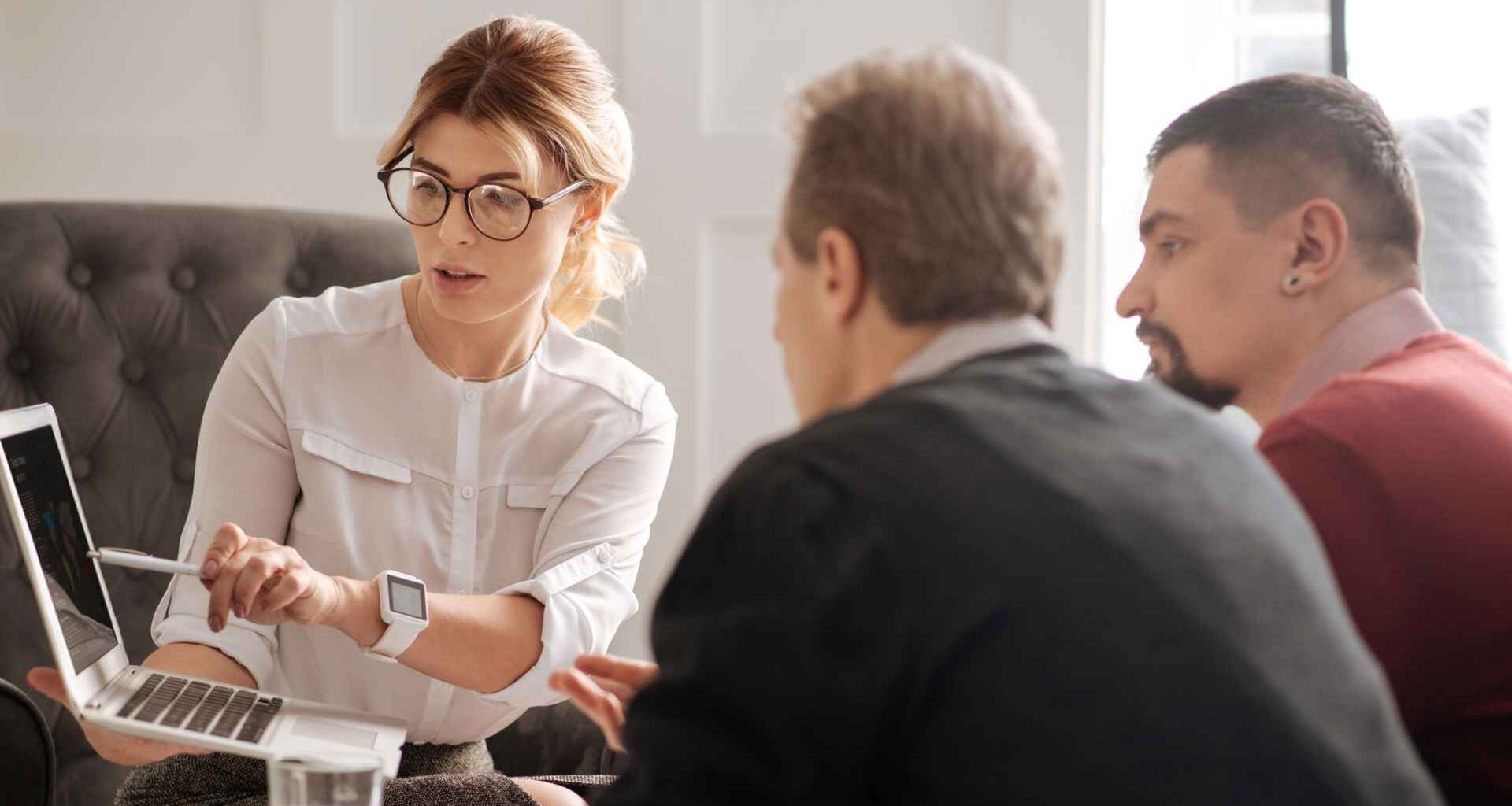 A group of colleagues sit together in a conference room and talk about work.
