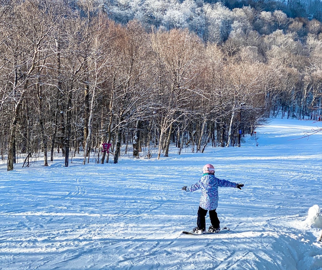 A young snowboarder descends a mountain slope.