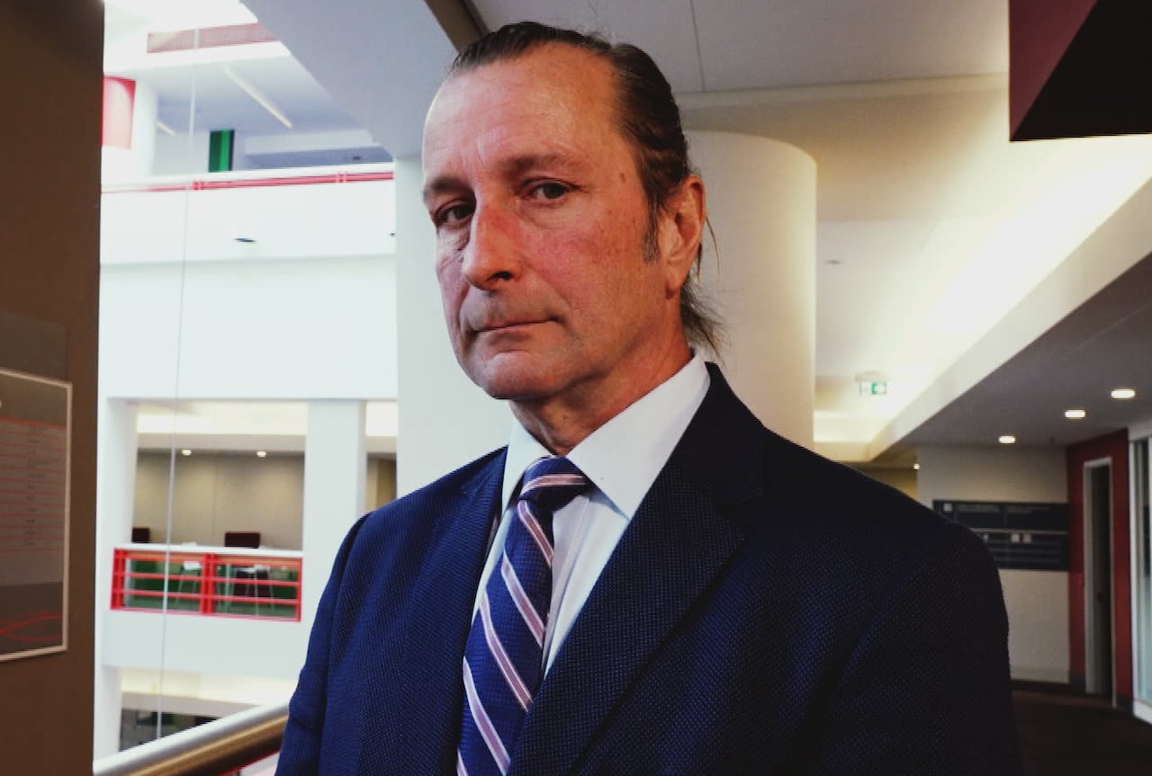 Man in suit and tie turned slightly to the side, looking down at camera