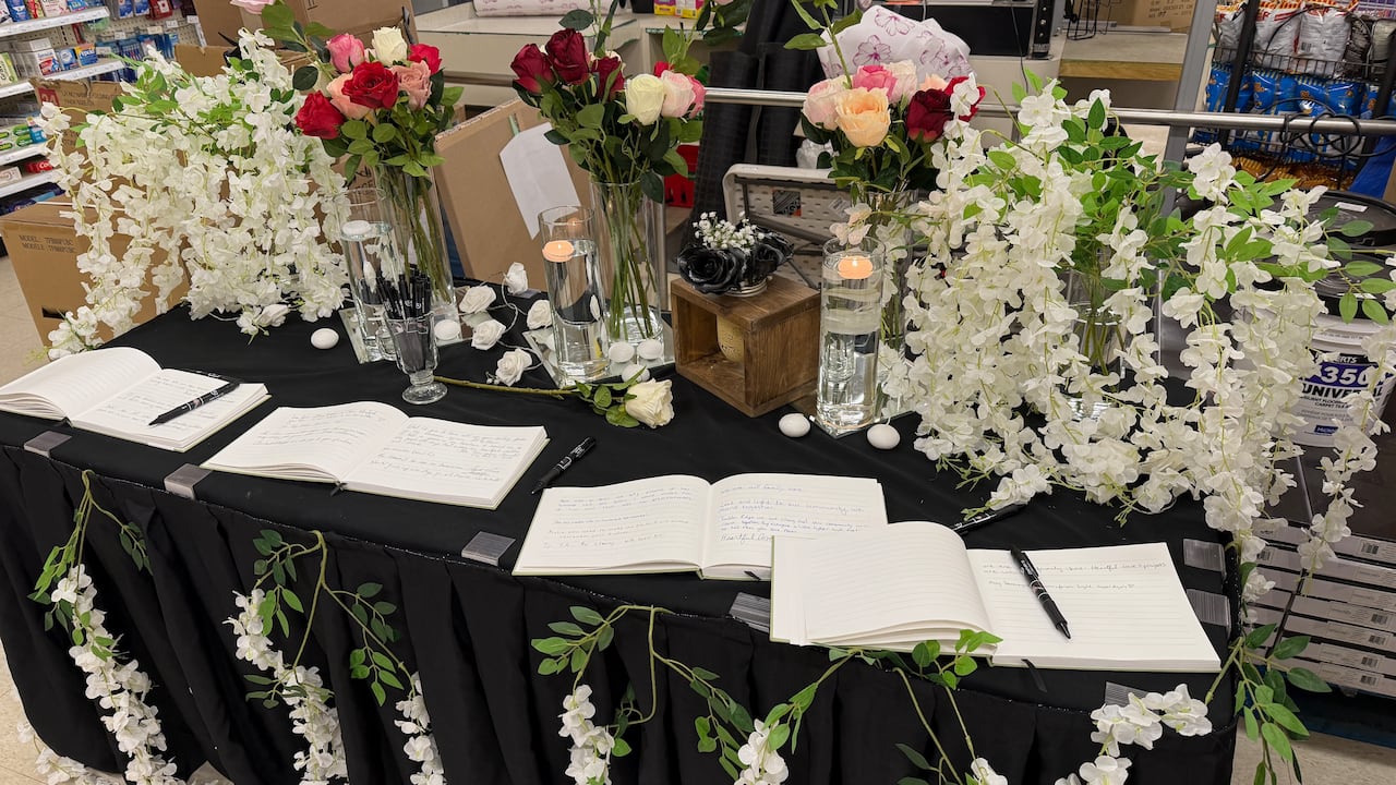 White notebooks lie open on a table covered in a black cloth and flowers. 