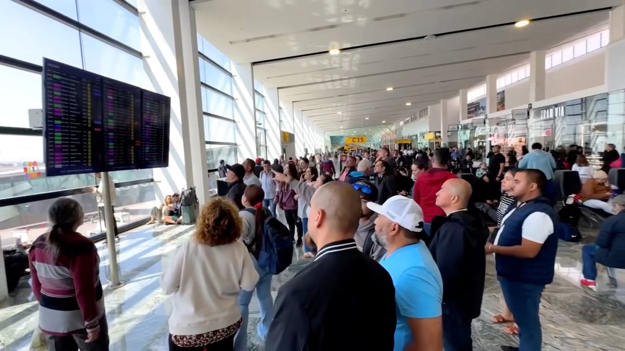 A group of people gather in front of a sign at an airport