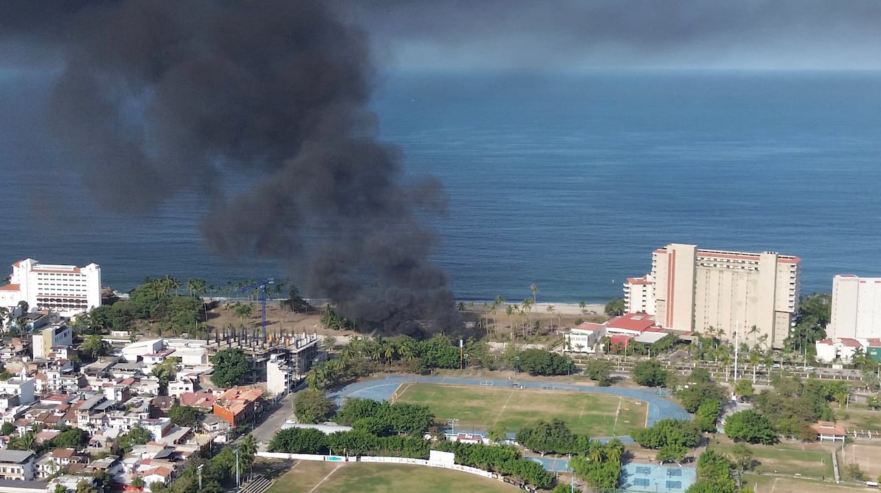 An aerial view of a seaside resort town, with smoke billowing into the air