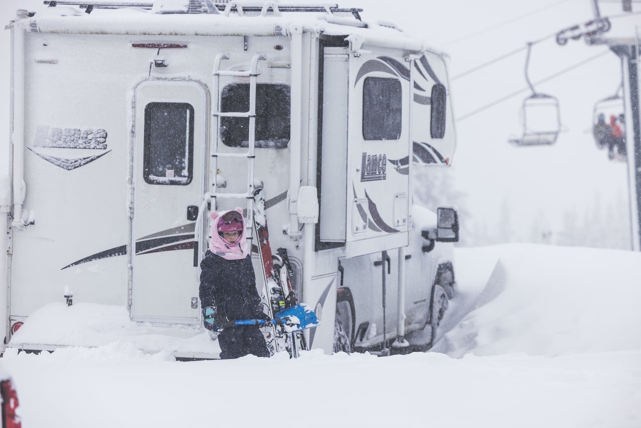 A snowboarder stands waist deep in the snow. 