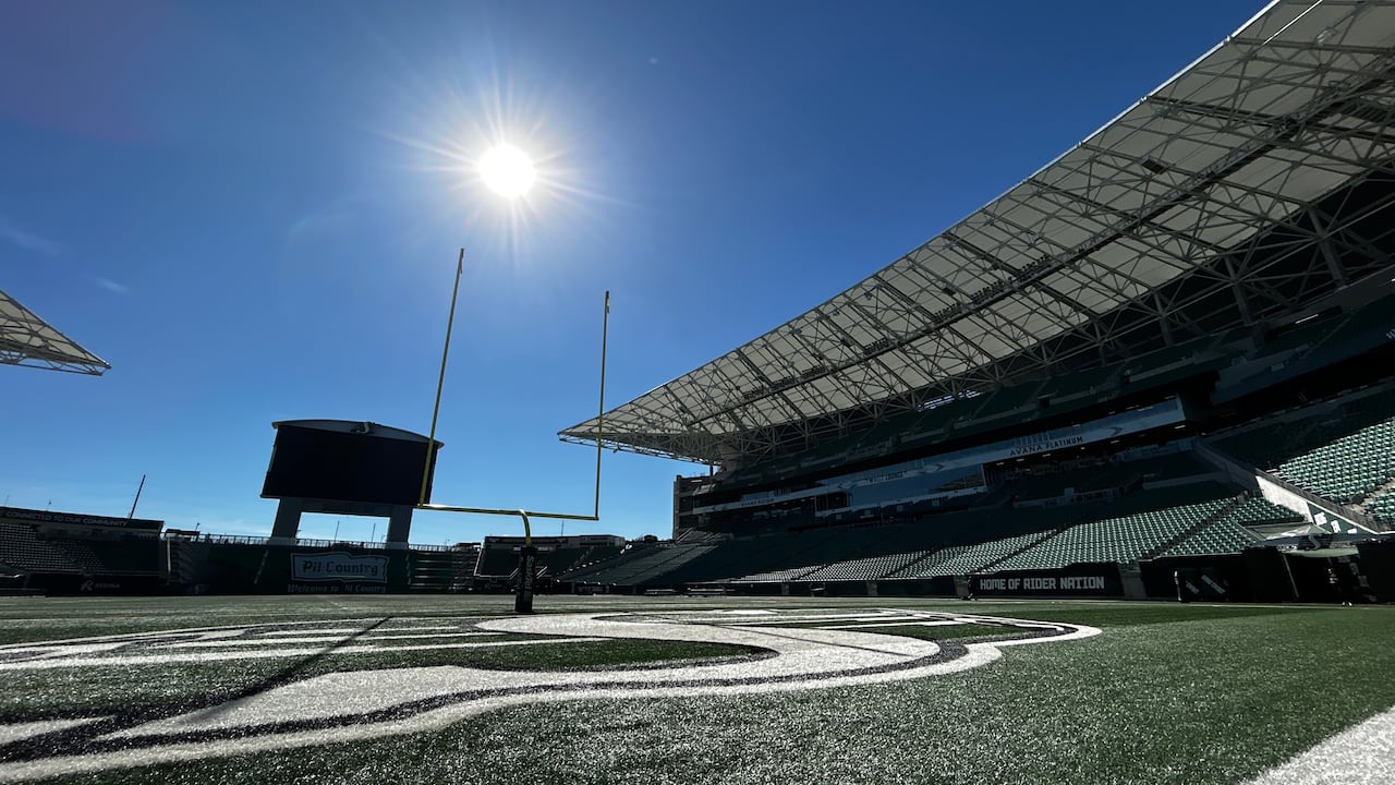 Men wearing green and black clothing speak to media that are holding microphones near their faces.