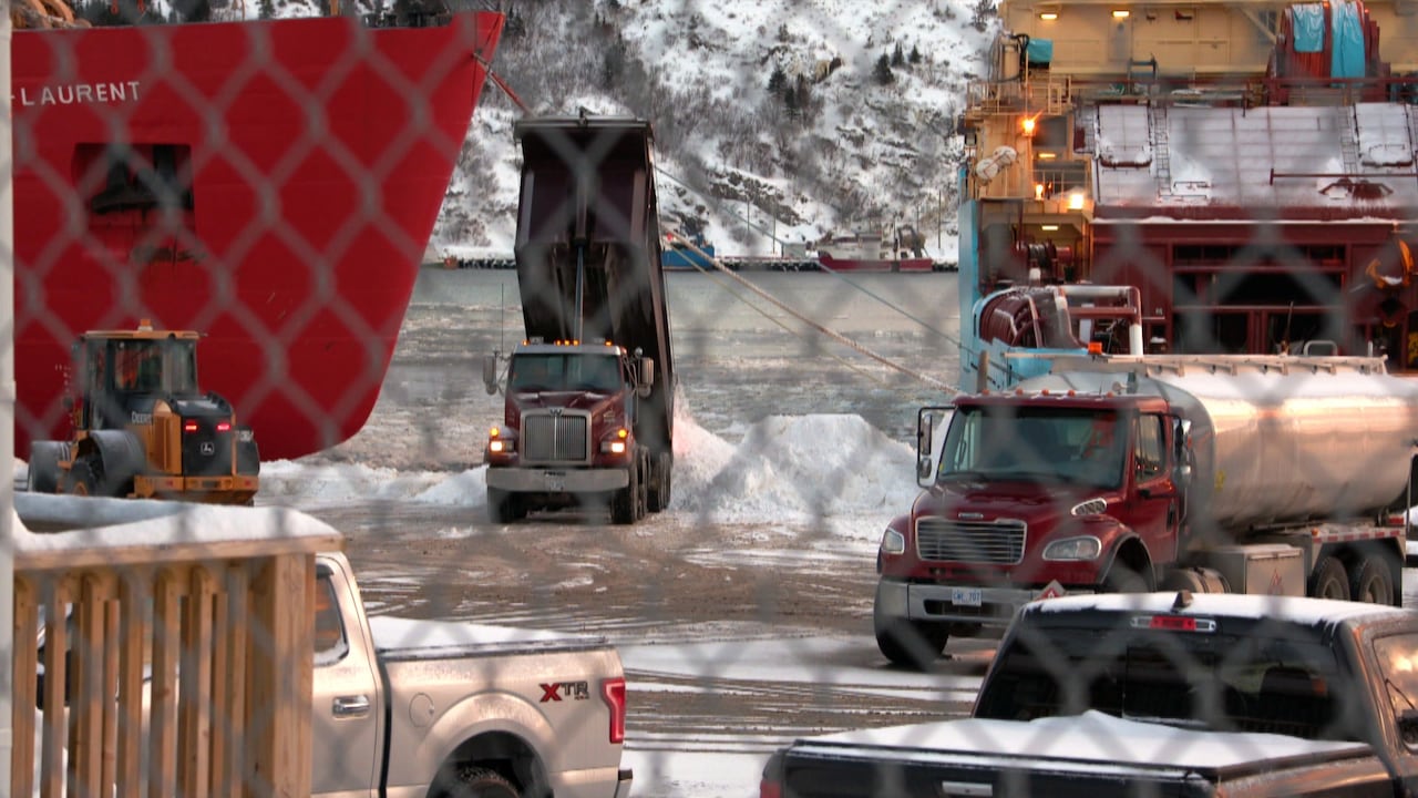 A dump truck offloading snow into water.
