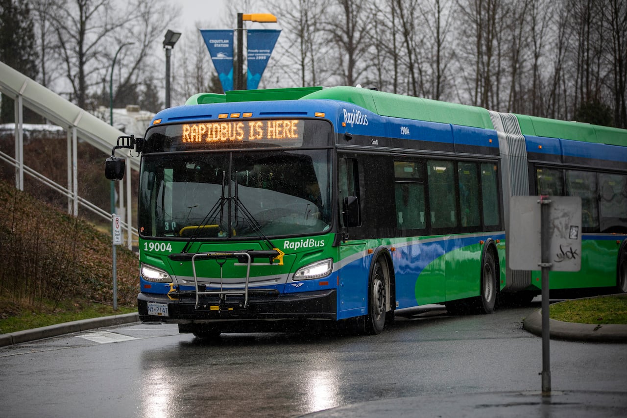 A green bus drives through a rainy street, with the words 'Rapidbus is here' on its chyron.