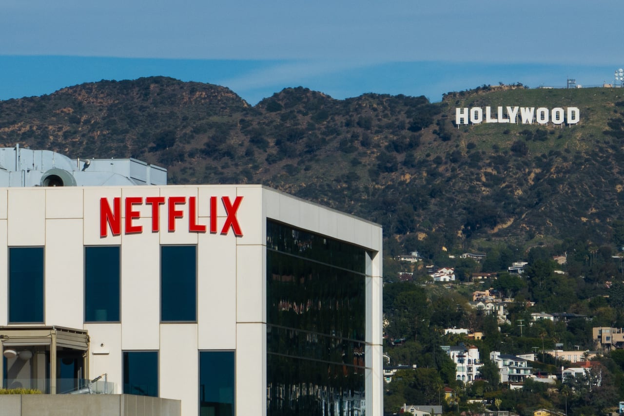 Exterior of a building with Netflix sign and Hollywood Hills and sign in distance 