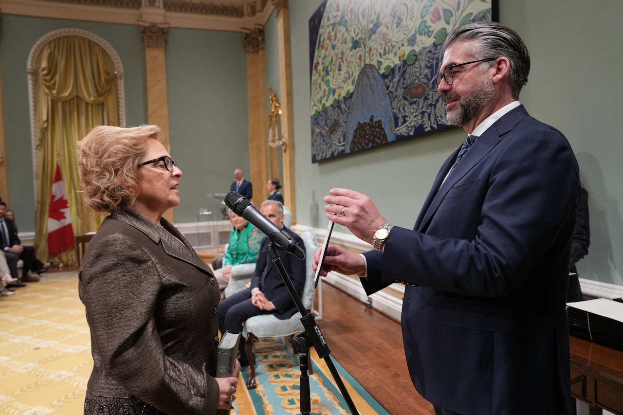 A woman speaking into a microphone in front of a man holding a script.
