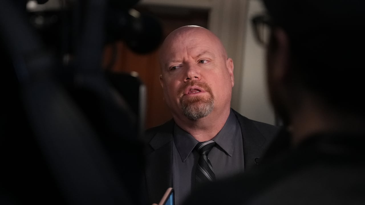 A man speaking with reporters