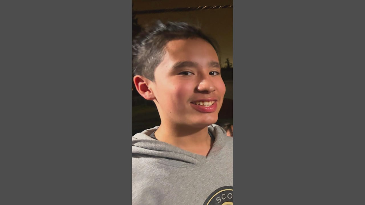 A smiling boy in a grey hoodie.